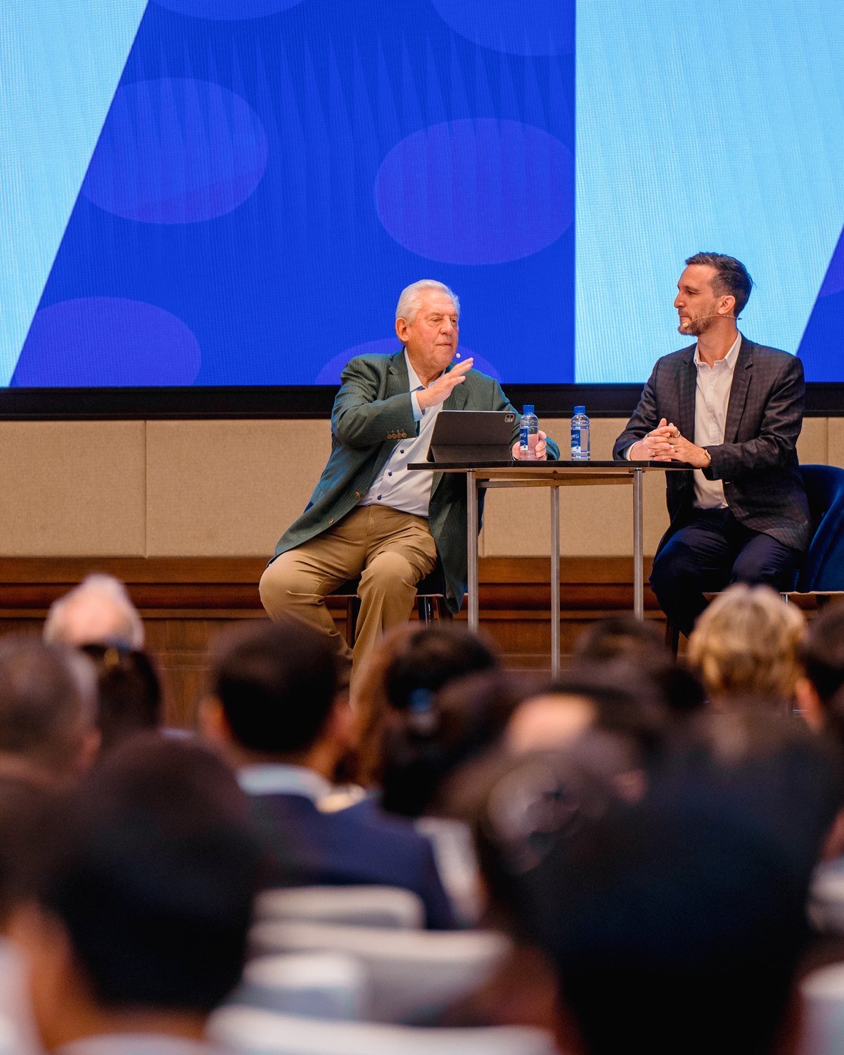 A fireside conversation on stage in front of a seated audience
