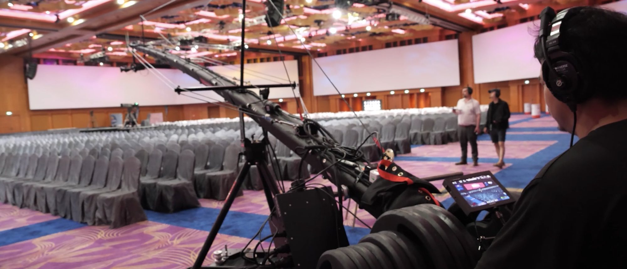 A camera operator on a jib crane rehearsing shots in a convention hall