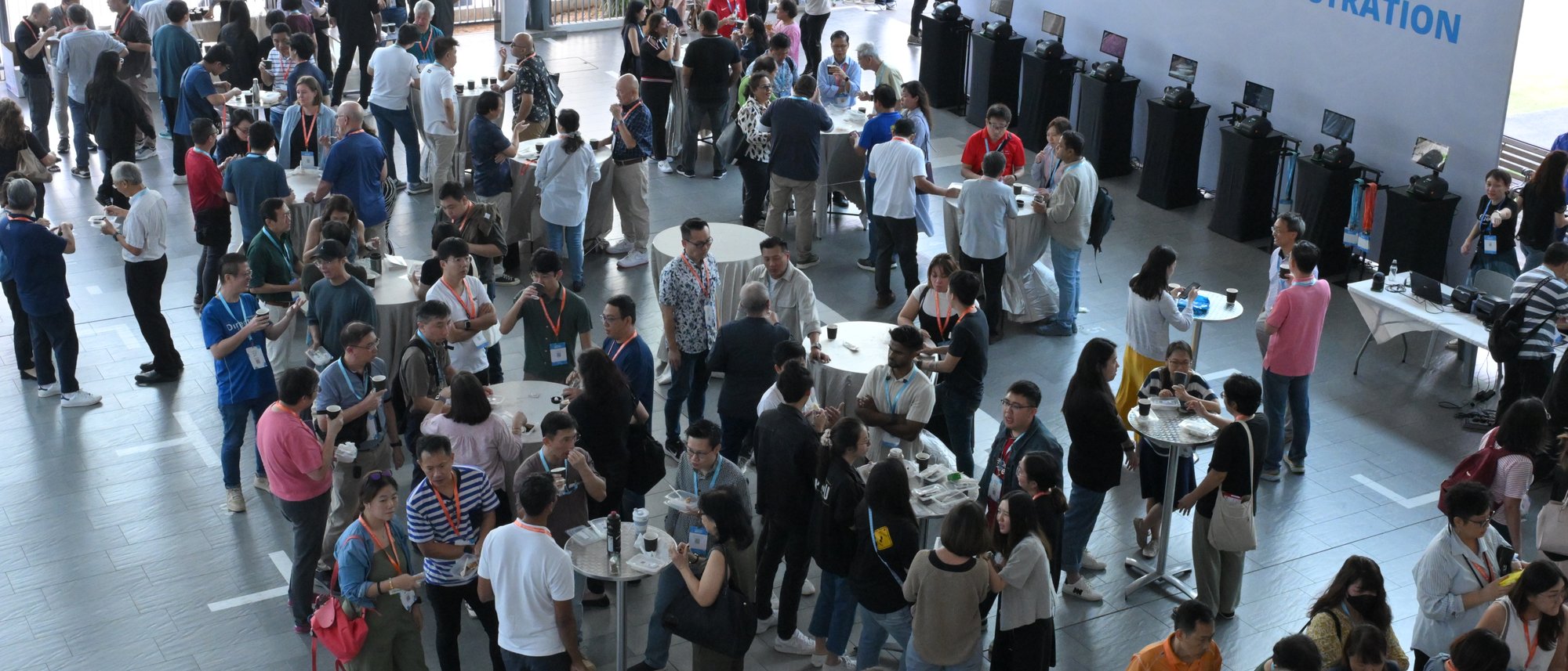 A busy registration hall seen from above, with guests checking in at rows of counters