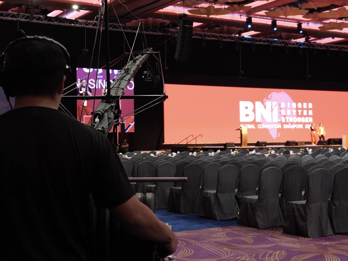 A camera operator filming the stage at a large convention