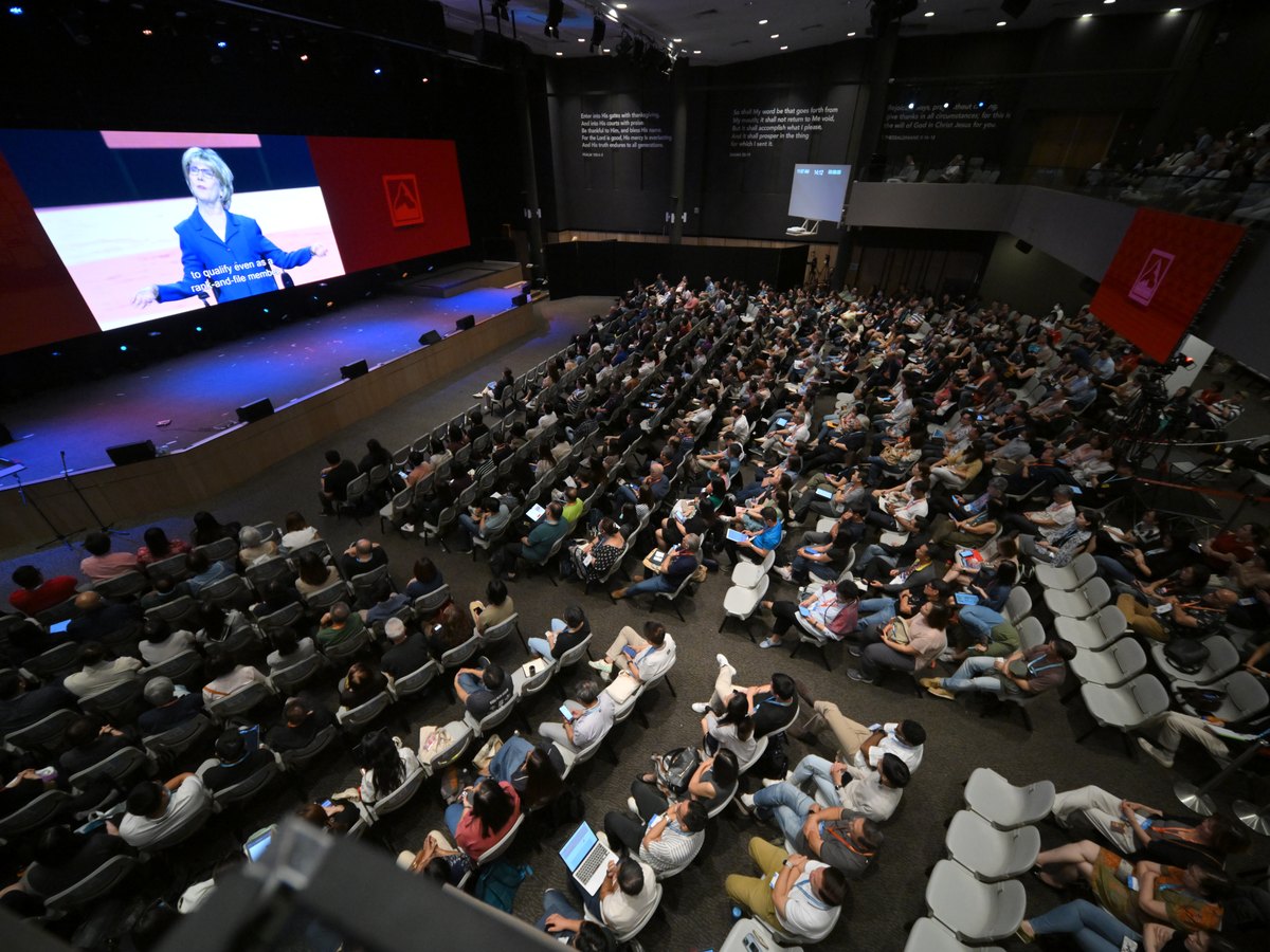 Aerial view of an auditorium, with the speaker on a large screen