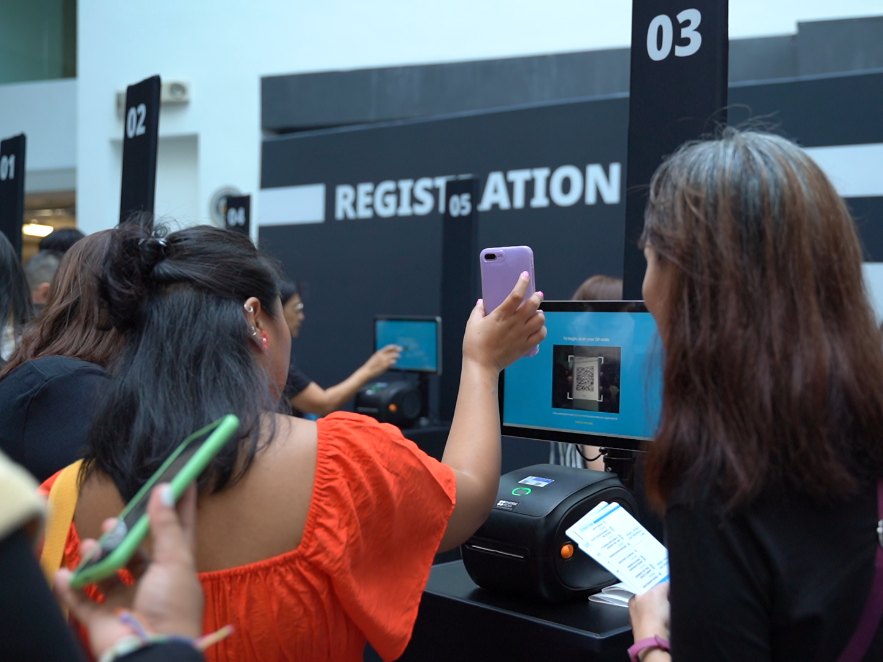 A delegate checking in with a phone at a registration counter