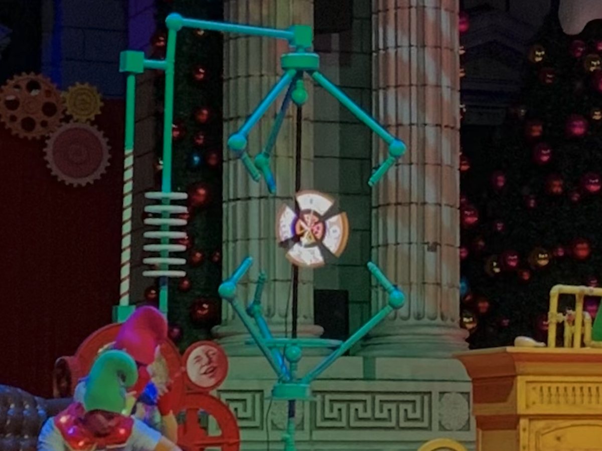 A holographic character appearing within a festive theatre set