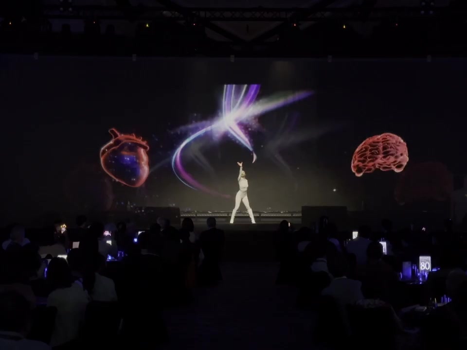 A dancer on stage between holographic organs, part of a launch performance