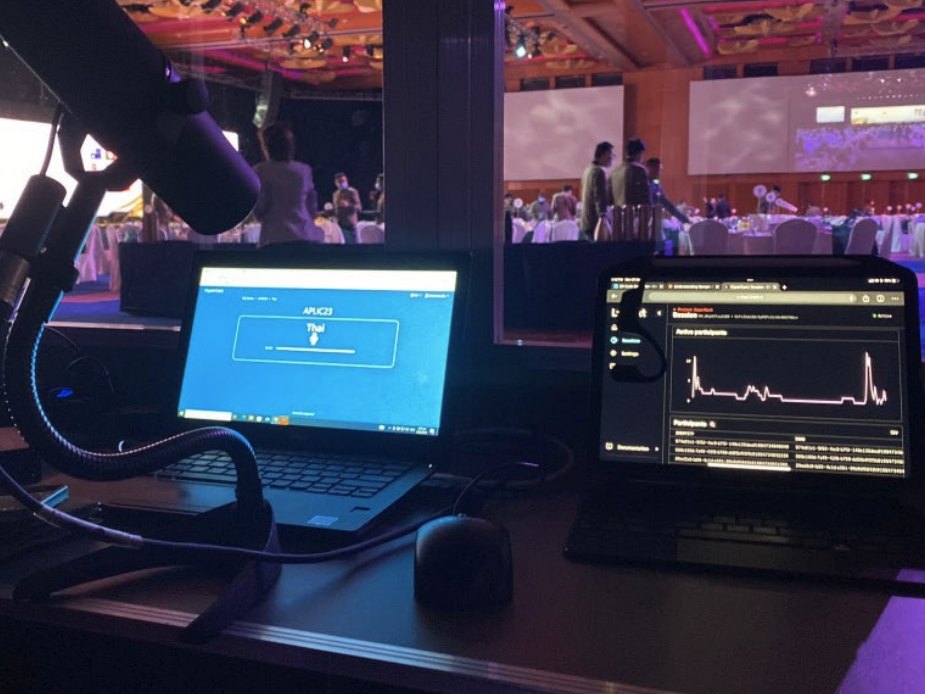 An interpretation desk with laptops, streaming a ballroom programme to phones through HyperCast