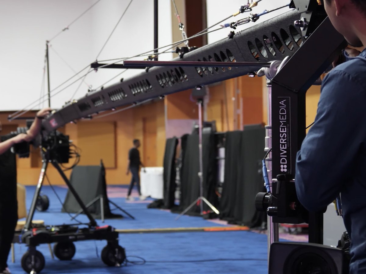 A camera crew rigging a jib crane in a convention hall