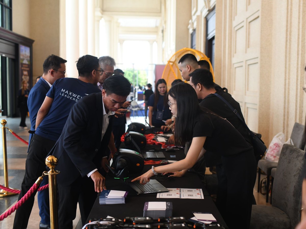 Staff at a registration counter helping guests check in, with badge printers along the table
