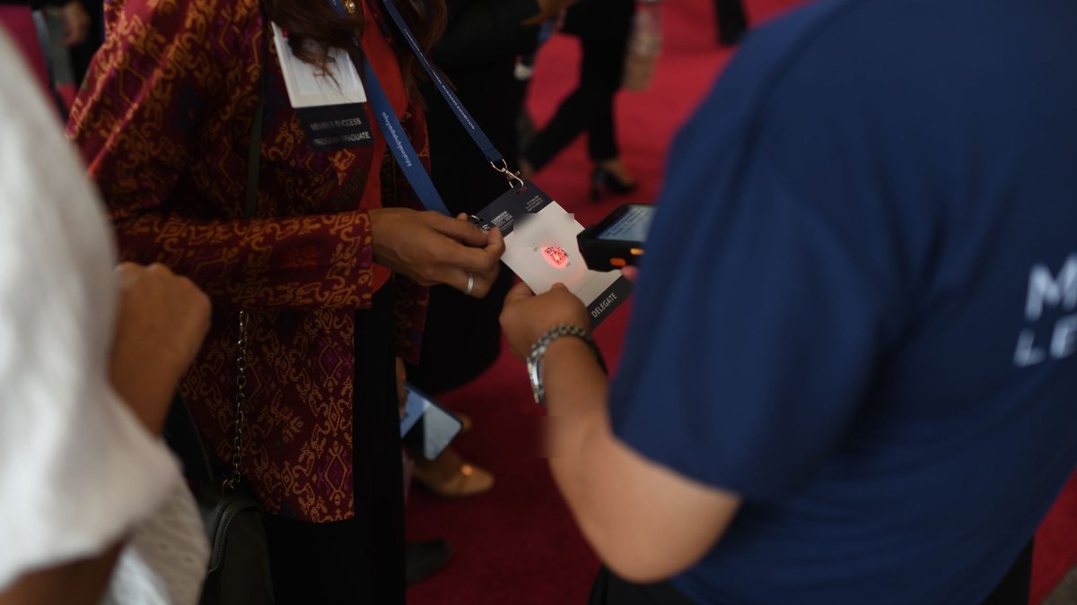 A delegate's badge scanned by hand at the door