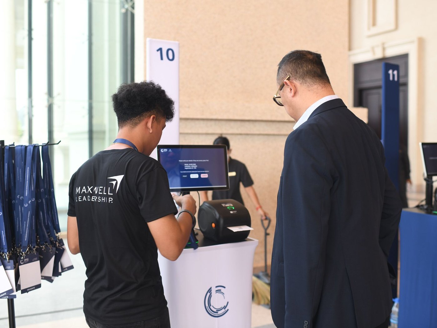 A delegate at a numbered check-in station while a staff member hands over the freshly printed badge