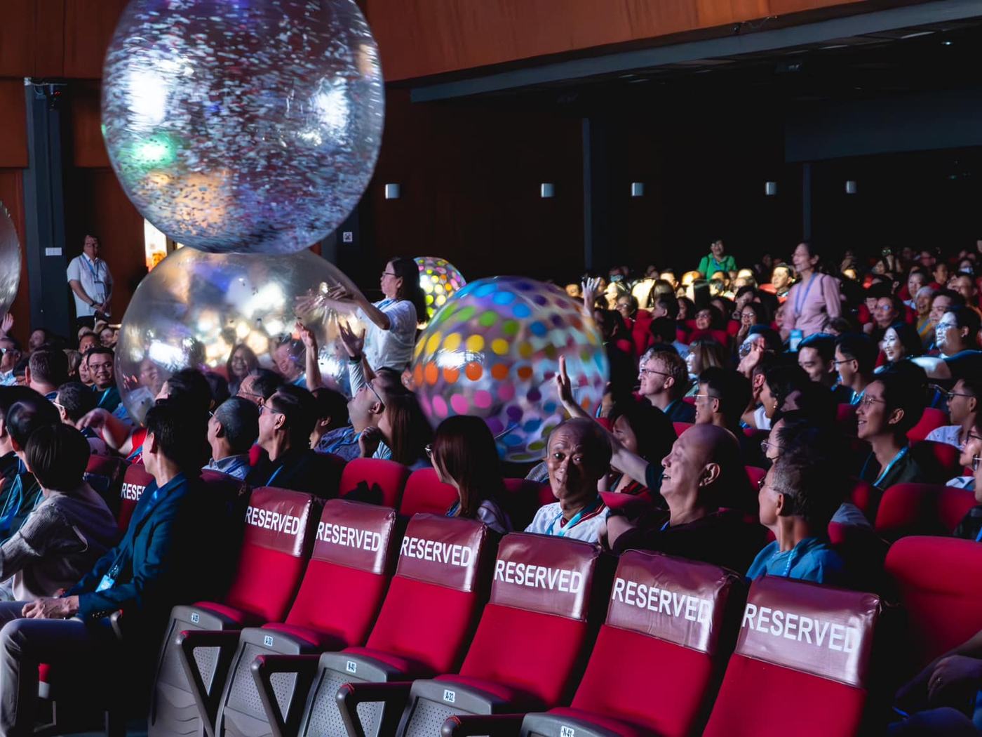 Summit guests in reserved seating beneath large inflatable globes, a creatively produced session