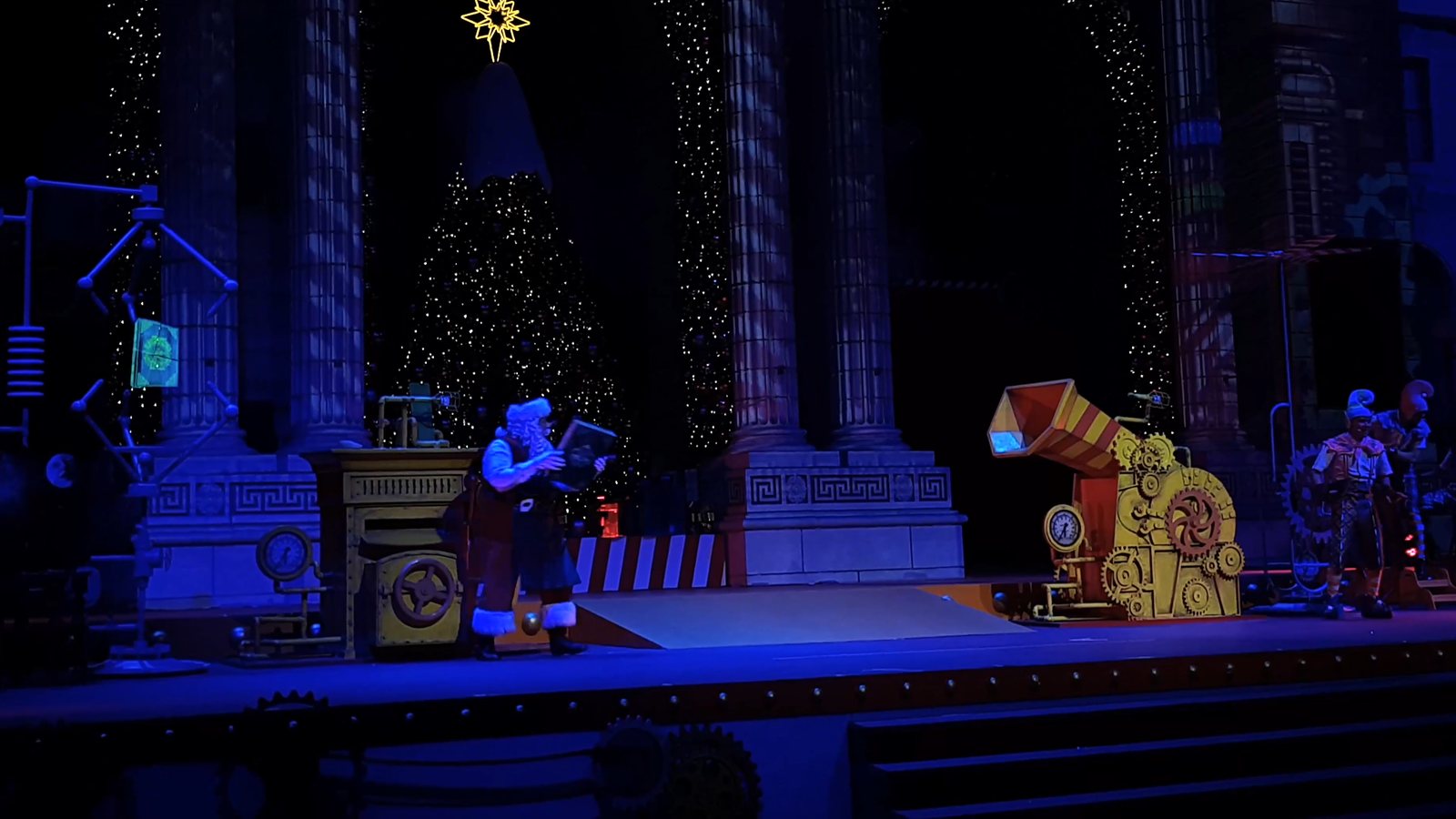 A holographic Christmas show on a theatre stage, with characters appearing among the set