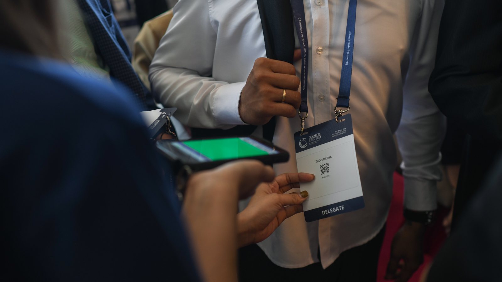 A delegate scans a QR code from a phone at a self-service kiosk to print a name badge
